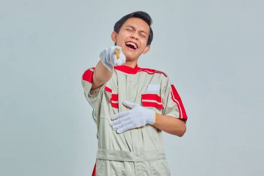 Mekanik üniforma giyen yakışıklı bir adamın portresi yüksek sesli kahkahalar atıyor, elleri karnında ve kamerayı işaret ediyor. 