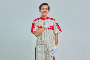 Genç tamircinin portresi Gri arka planda izole edilmiş yüzünde büyük bir gülümsemeyle selamlıyor.