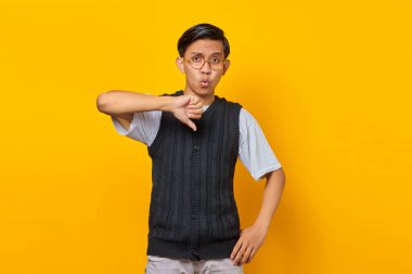 Asyalı genç adam mutsuz ve kızgın görünüyor. Başparmağıyla reddediliyor.