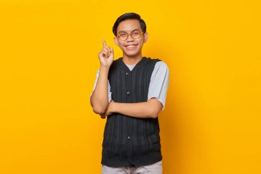 Heyecanlı genç adam parmağını kaldırıyor ve sarı arka planda yaratıcı bir fikri var.