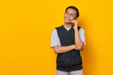 Cep telefonundan konuşan ve sarı arka plana bakan neşeli Asyalı adamın portresi.