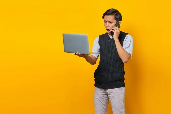 Geschokt Knappe Jonge Man Praten Smartphone Kijken Naar Laptop Scherm — Stockfoto