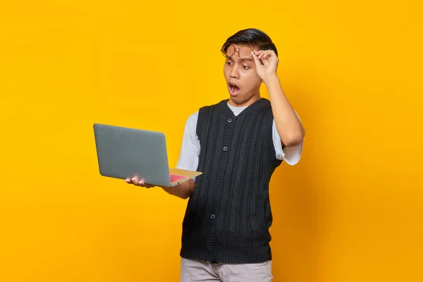 用笔记本电脑和眼镜隔离在黄色背景下的亚洲年轻人震惊了 — 图库照片