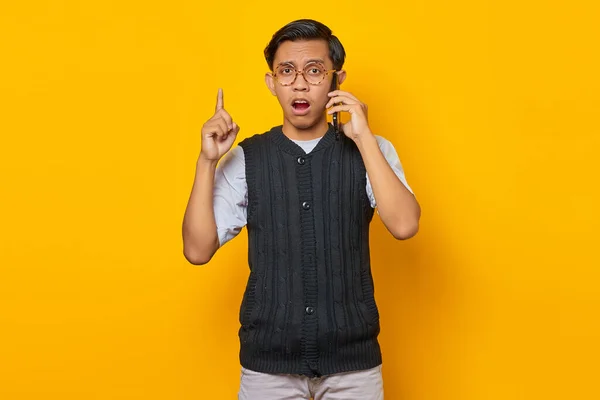 Cep Telefonuyla Konuşan Sarı Arka Planı Işaret Eden Asyalı Genç — Stok fotoğraf