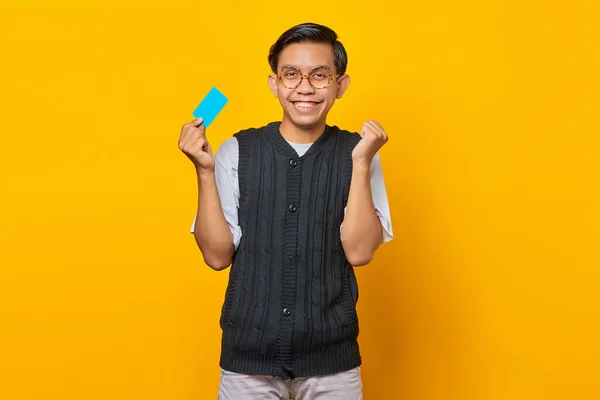 Opgewonden Jonge Aziatische Man Met Credit Card Geïsoleerd Gele Achtergrond — Stockfoto