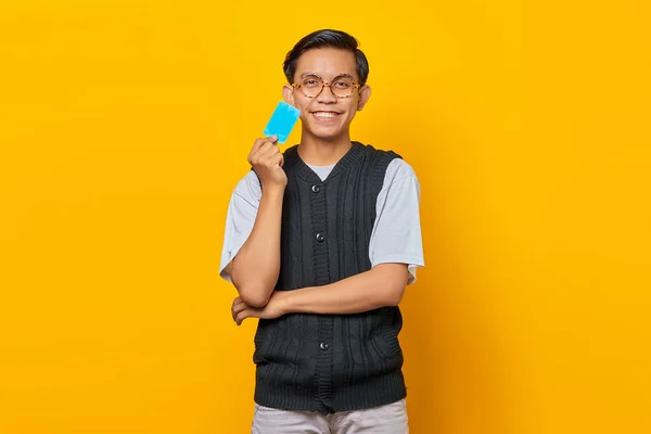 Посміхаючись Молодий Азіат Тримає Руках Кредитну Картку Дивиться Камеру Жовтому — стокове фото