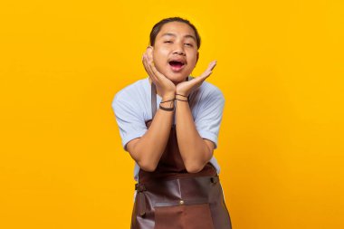 Önlük takmış neşeli Asyalı genç adam portresi Sarı arka grubunda ileriye bakıyor