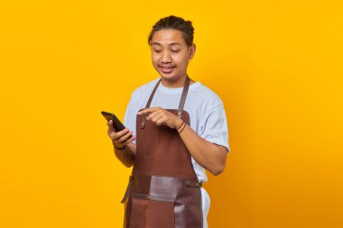 Önlük giymiş Asyalı genç adamın portresi sarı arka planda akıllı telefondan gelen mesajı görünce şaşırdı.