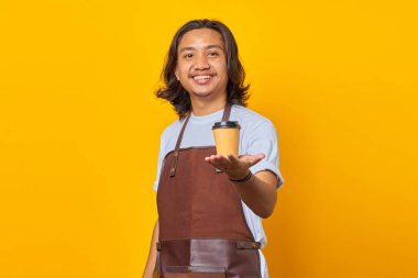 Elleriyle kağıt bardak tutan neşeli ve pozitif yakışıklı bir adamın portresi. Kahvenin tadına bakmanı tavsiye ediyor.