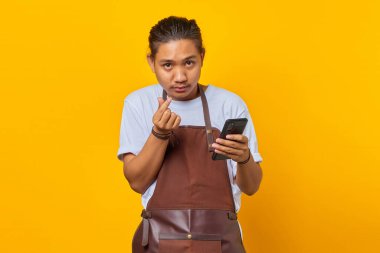 Neşeli Asyalı bir gencin portresi. Parmağını gösteren ve elinde akıllı telefon tutan.