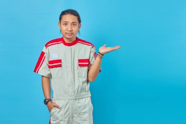 Mekanik üniforma giyen üzgün yakışıklı adamın portresi mavi arka planda fotokopi alanını gösteriyor