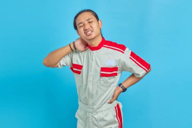 Boynu ağrıyan ve elleriyle dokunan mekanik üniforma giyen yakışıklı bir adam.