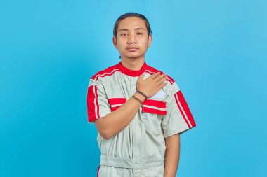 Yakışıklı tamirci yüzünde neşeli bir gülümsemeyle mavi arka planda izole edilmiş.