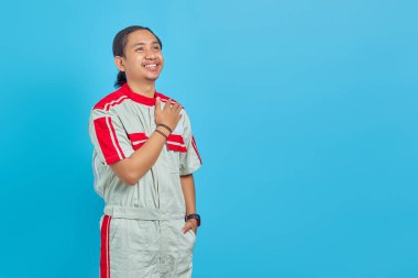 Yakışıklı tamirci boşluğu selamlıyor. Yüzünde neşeli bir gülümseme var. Mavi arka planda izole edilmiş.