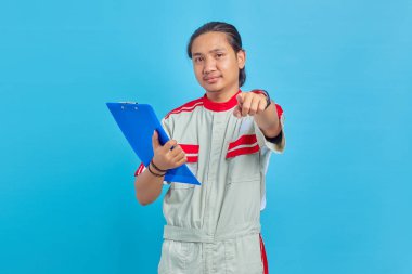 Elinde not panosu olan ve mavi arka planda izole edilmiş mutlu ve yakışıklı mekanik bir adamın portresi.