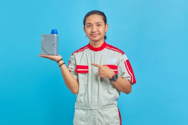 Motor yağı şişesini mavi arka planda gösteren, mekanik üniforma giyen neşeli yakışıklı adamın portresi.