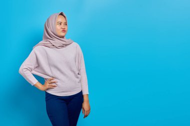 Neşeli Asyalı kadın mavi arka planda kameraya bakıyor.