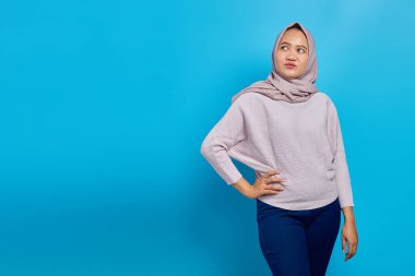 Neşeli Asyalı kadın mavi arka planda kameraya bakıyor.