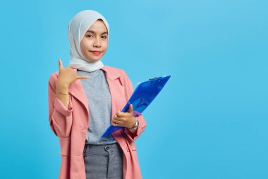 Güzel bir kadının portresi. Elinde klasör var ve mavi arka planda telefon görüşmesi yapıyor.