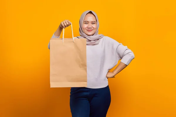 黄色の背景にショッピングバッグを保持している陽気なアジアの女性の肖像画 — ストック写真