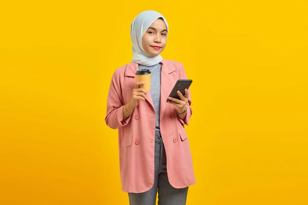 明るいアジアの若い女性の携帯電話を保持し 青い背景にコーヒーを運ぶの肖像画 — ストック写真