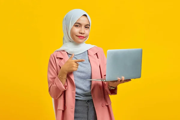 Portrait Smiling Young Asian Woman Holding Laptop Pointing Isolated Yellow — Stock Photo, Image