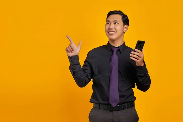 Gelukkig Jong Aziatisch Man Holding Mobiele Telefoon Wijzend Vinger Naar — Stockfoto