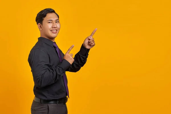 Portrét Usmívajícího Mladého Asijského Podnikatele Ukazující Prstem Kopírovací Prostor Žlutém — Stock fotografie