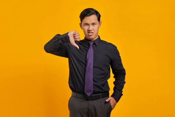 Розгніваний Молодий Азійський Бізнесмен Який Тримає Великі Пальці Жовтому Фоні — стокове фото