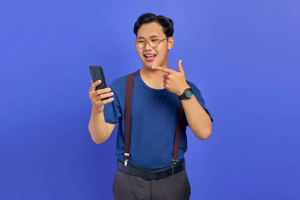 Potret Pria Tersenyum Menunjuk Jari Ponsel Pada Latar Belakang Ungu — Stok Foto