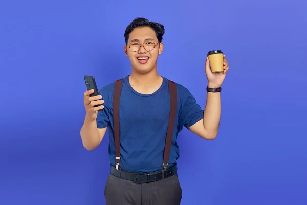 Усміхнений Молодий Чоловік Тримає Смартфон Чашку Кави Фіолетовому Фоні — стокове фото