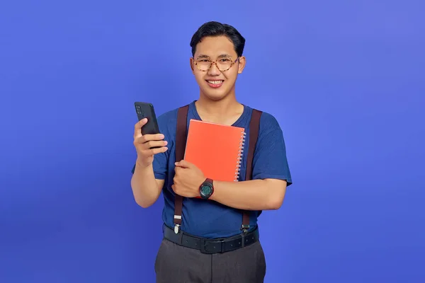 Smiling Young Asian Man Holding Cell Phone Notebook Purple Background — Stock Photo, Image
