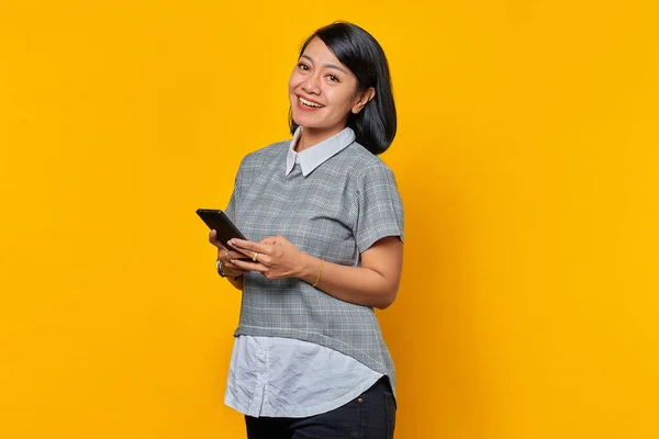 Retrato Sorrir Jovem Mulher Asiática Segurando Telefone Celular Fundo Amarelo — Fotografia de Stock