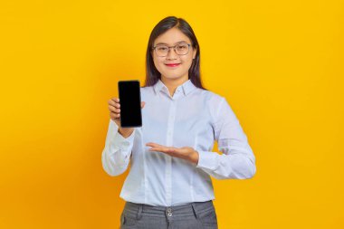 Neşeli Asyalı kadının fotoğrafı. Sarı arka planda avuçları olan boş akıllı telefon ekranı gösteriyor.