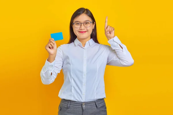 Photo Smiling Asian Woman Holding Credit Card Pointing Yellow Background — Stock Photo, Image