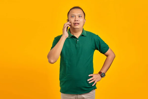 Здивований Молодий Азіат Розмовляє Мобільному Телефону Кладе Руки Жовте Тло — стокове фото