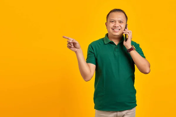 Посміхнений Азіатський Чоловік Розмовляє Мобільному Телефону Вказуючи Пальцем Копіювальний Простір — стокове фото