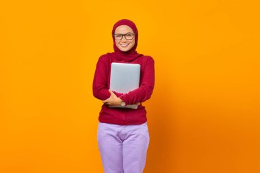 Gülümseyen Asyalı kadının portresi sarı arka planda dizüstü bilgisayar getiriyor.