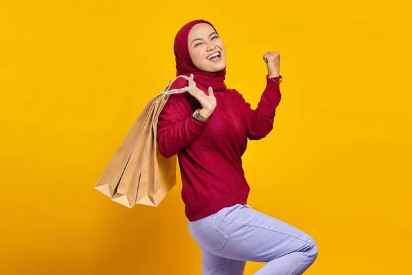 黄色の背景にショッピングバッグを持って興奮し 陽気な若いアジアの女性 — ストック写真