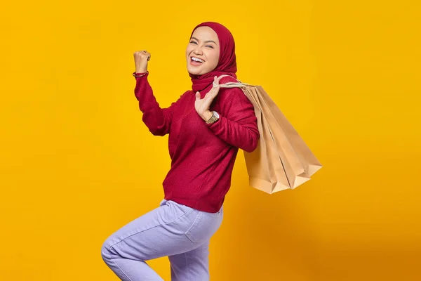 黄色の背景にショッピングバッグを持って興奮し 陽気な若いアジアの女性 — ストック写真