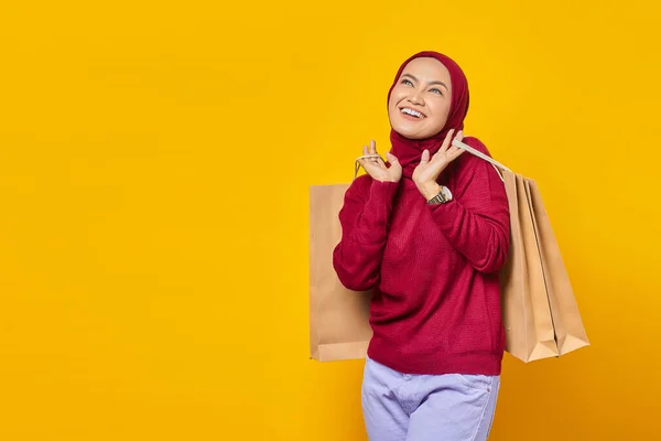 Boldog Fiatal Ázsiai Kezében Bevásárló Táskák Felnézett Sárga Háttér — Stock Fotó
