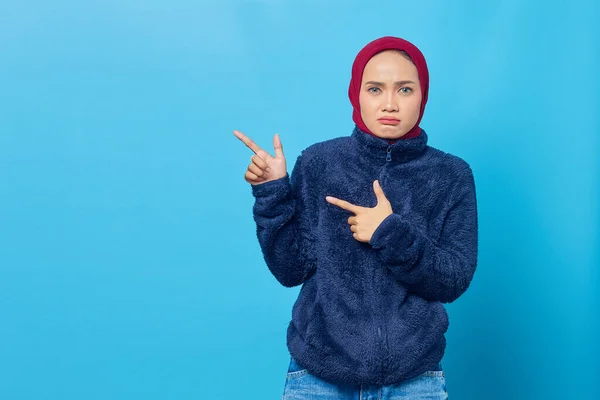 Portret Zamyślonej Młodej Azjatki Wskazującej Palcem Przestrzeń Niebieskim Tle — Zdjęcie stockowe