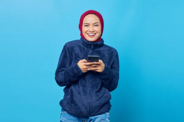 Портрет Улыбающейся Молодой Азиатки Помощью Мобильного Телефона Синем Фоне — стоковое фото