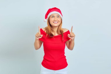 Neşeli genç Asyalı kadın beyaz arka planda izole edilmiş fotokopi alanını işaret ediyor.