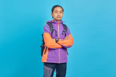 Smiling young Asian man with crossed arms looking at camera on blue background