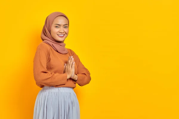 茶色のセーターで笑顔若いアジアのイスラム教徒の女性の肖像画は 黄色の背景に隔離された顧客を迎えるために自信を持って オープンサインを見て — ストック写真