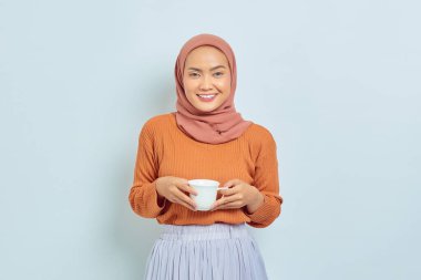 Kahverengi süveter ve el ele tutuşan gülümseyen Asyalı genç kadın portresi beyaz arka planda izole edilmiş.