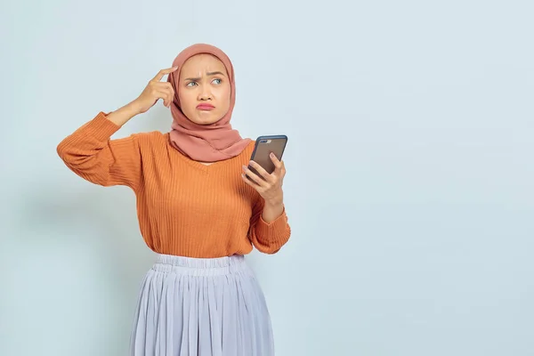 Портрет Смущенной Молодой Азиатки Мусульманки Коричневом Свитере Хиджаб Держащей Смартфон — стоковое фото