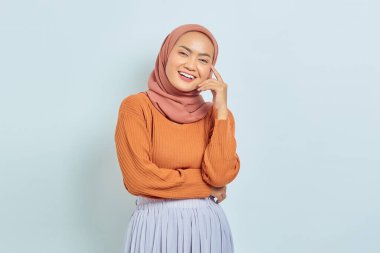 Kahverengi kazaklı güzel Asyalı Müslüman kadın portresi ve beyaz arka planda izole edilmiş kameraya bakışı. Müslüman yaşam tarzı kavramı