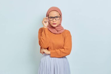 Kahverengi süveter ve gözlüklü genç Asyalı Müslüman kadın, beyaz arka planda izole edilmiş bir şeyi düşünürken çenesini tutuyor. İnsanlar dini yaşam tarzı konsepti